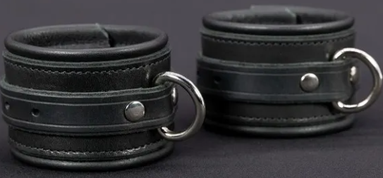 A pair of thick black leather cuffs